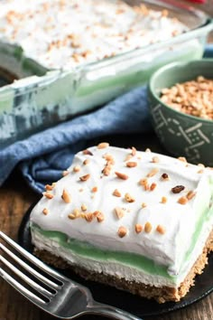 a piece of cake with white frosting and nuts on top next to a fork