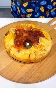 a wooden cutting board topped with food on top of a white table next to a woman's face