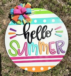 a painted sign that says hello summer on the grass with a bow in front of it