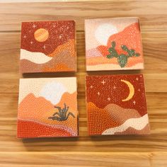 four square coasters with desert scenes painted on them, sitting on a wooden surface