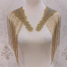 a white mannequin with gold fringes on it's neck and back