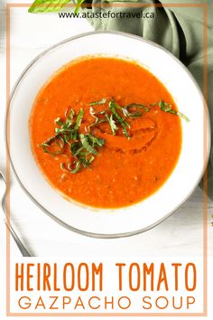 a bowl of red tomato soup with basil on top and the words heir tomato gazpacho soup above it