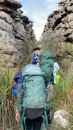 two people with backpacks walking up a trail