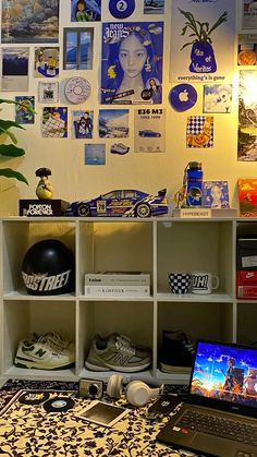 a laptop computer sitting on top of a desk next to a wall covered in pictures