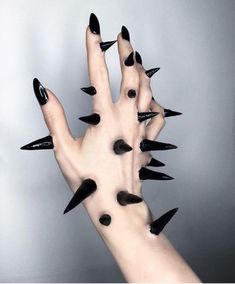 a woman's hand with black nails and spikes on it