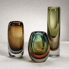 three different colored glass vases sitting next to each other