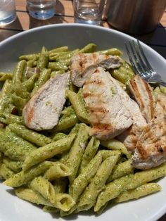 a white plate topped with green pasta and meat