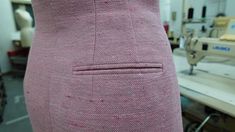 the back of a woman's pink dress in a sewing room with tools and equipment