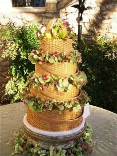 a three tiered cake sitting on top of a table covered in flowers and greenery