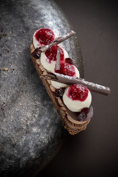 a piece of bread with cream and strawberries on it sitting on top of a rock