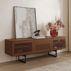 a wooden sideboard with a mirror and vase on top