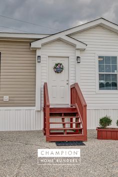 a white house with red steps leading up to the front door and entryway that has a wreath on it