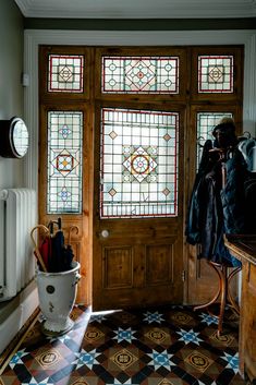 an entryway with stained glass windows and coat rack on the door, in front of a tiled floor