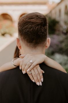 a man and woman embracing each other with their hands on the back of his shoulder