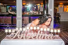 a woman leaning over a table with candles in front of her and the word alohnia written on it