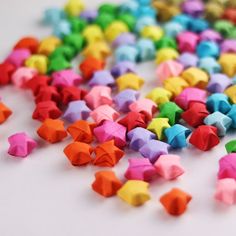 colorful origami stars are scattered on a white surface