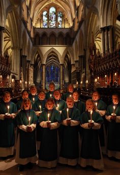 a group of people holding lit candles in front of a large cathedral with stained glass windows