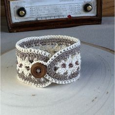 a crocheted cuff with buttons on it sitting next to an old fashioned radio