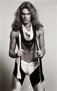 a man with long hair and no shirt on holding two ties around his neck while standing in front of a white background