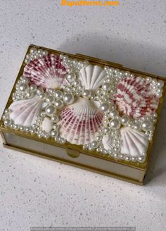 a box with pearls and seashells in it on a white counter top,