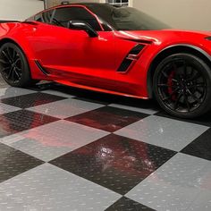 a red sports car is parked on a checkerboard floor in a showroom