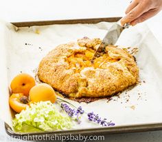 a person cutting into a pie on top of a pan filled with fruits and vegetables