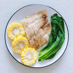 a white plate topped with fish, broccoli and sliced yellow peppers on top of it