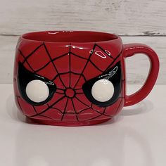 a red spiderman mug sitting on top of a table