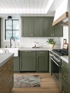 a kitchen with green cabinets and white counter tops, an area rug on the floor