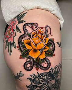 a woman's thigh with tattoos on it and a snake around the flower tattoo