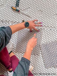 a woman sitting on the floor with her hands in front of some fabric and scissors