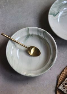 two white plates with gold spoons on them