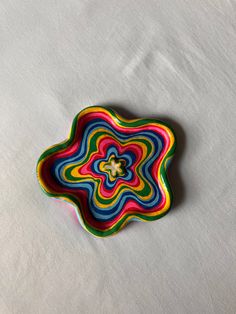 a colorful plate sitting on top of a white tablecloth covered floor next to a wall