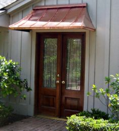 a white house with a brown door and brick walkway