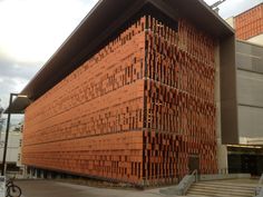 a large building made out of red bricks on the side of a street with stairs leading up to it