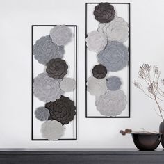 two metal wall art pieces with flowers on them in front of a fireplace mantel