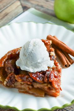 a slice of apple pie with ice cream on top and cinnamon sticks in the background