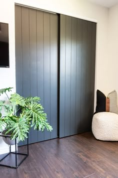 a living room with wooden flooring and black sliding doors leading to a tv mounted on the wall