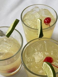 three glasses filled with drinks and garnished with lime, cherries, and a cherry