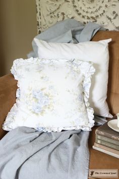 a pillow and some books on a couch next to a chair with a white headboard