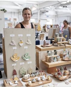 a woman standing next to a table filled with different types of earrings and figurines