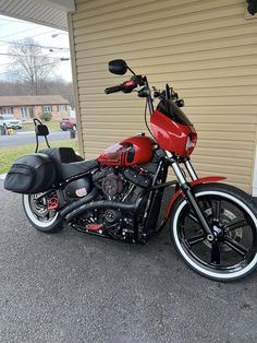 a red motorcycle parked in front of a garage