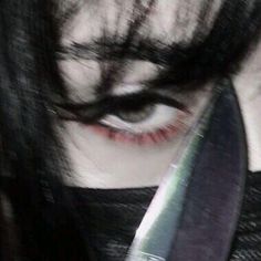 a close up of a person holding a knife in front of their face and looking at the camera