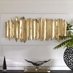 a black table topped with a vase filled with green plants and gold foil strips hanging from it's sides