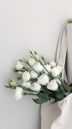 a bouquet of white tulips sits in front of a tote bag