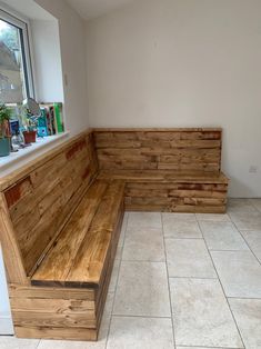 a wooden bench sitting on top of a white tiled floor next to a large window