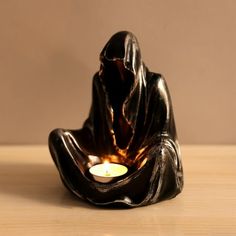 a candle that is sitting in the shape of a person with a hooded figure on it