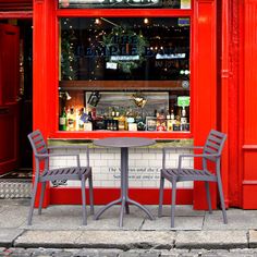 two chairs and a table in front of a red building with a sign that says bistro