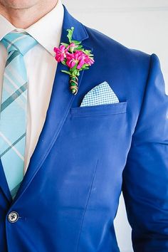 a man in a blue suit with a pink flower on his lapel and pocket square