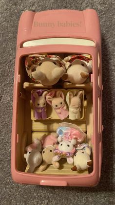 a pink toy cell phone with many stuffed animals in it's back compartment and the words bunny babies written on its side